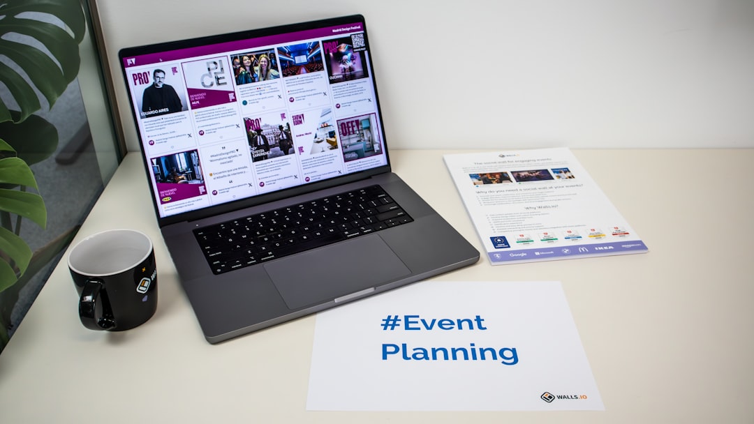 A desk with an event flyer, a piece of paper with the hashtag #EventPlanning and a laptop showing a social media wall